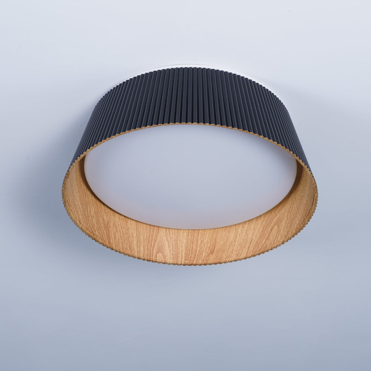 Black Clérachic ceiling light seen from a low angle, with a frosted diffuser inside its wood-grain rim.