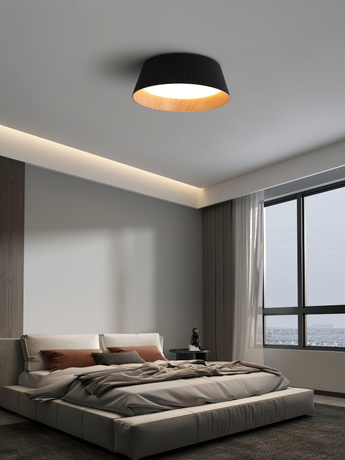 A black Clérachic ceiling light in a bedroom with a low grey bed, a concealed strip light and a large window.