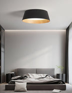 Black Clérachic ceiling light over a grey bed with a padded headboard, in a calm room with floor-length curtains.
