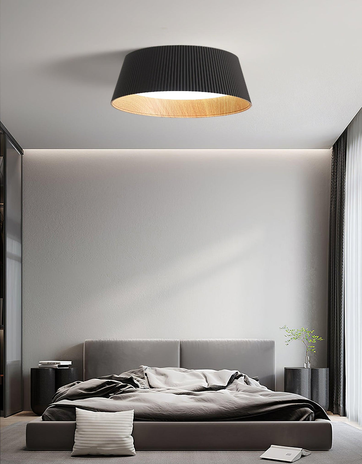 Black Clérachic ceiling light over a grey bed with a padded headboard, in a calm room with floor-length curtains.