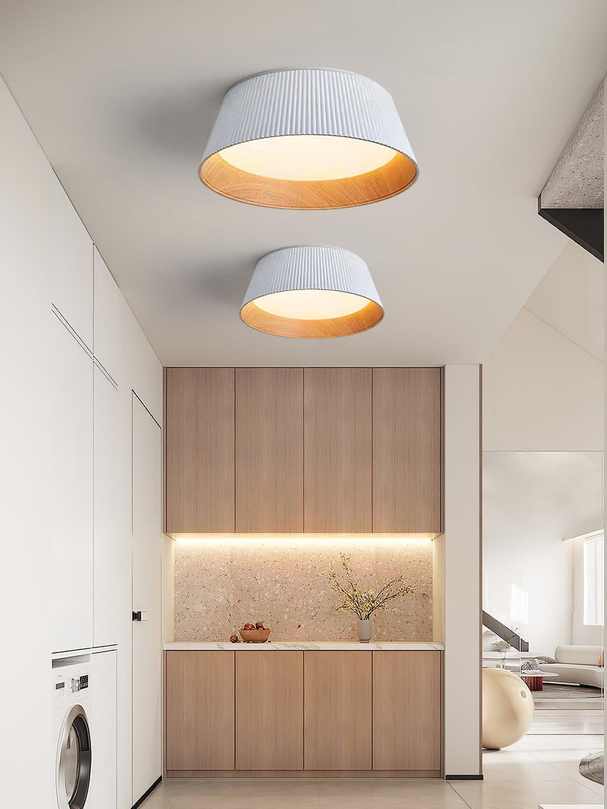 Two white Clérachic ceiling lights, one above the other, in a corridor with timber cabinets and a washing machine.