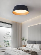 Black Clérachic ceiling light above a bright bedroom with a grey bed, a potted plant and a fluted white feature wall.