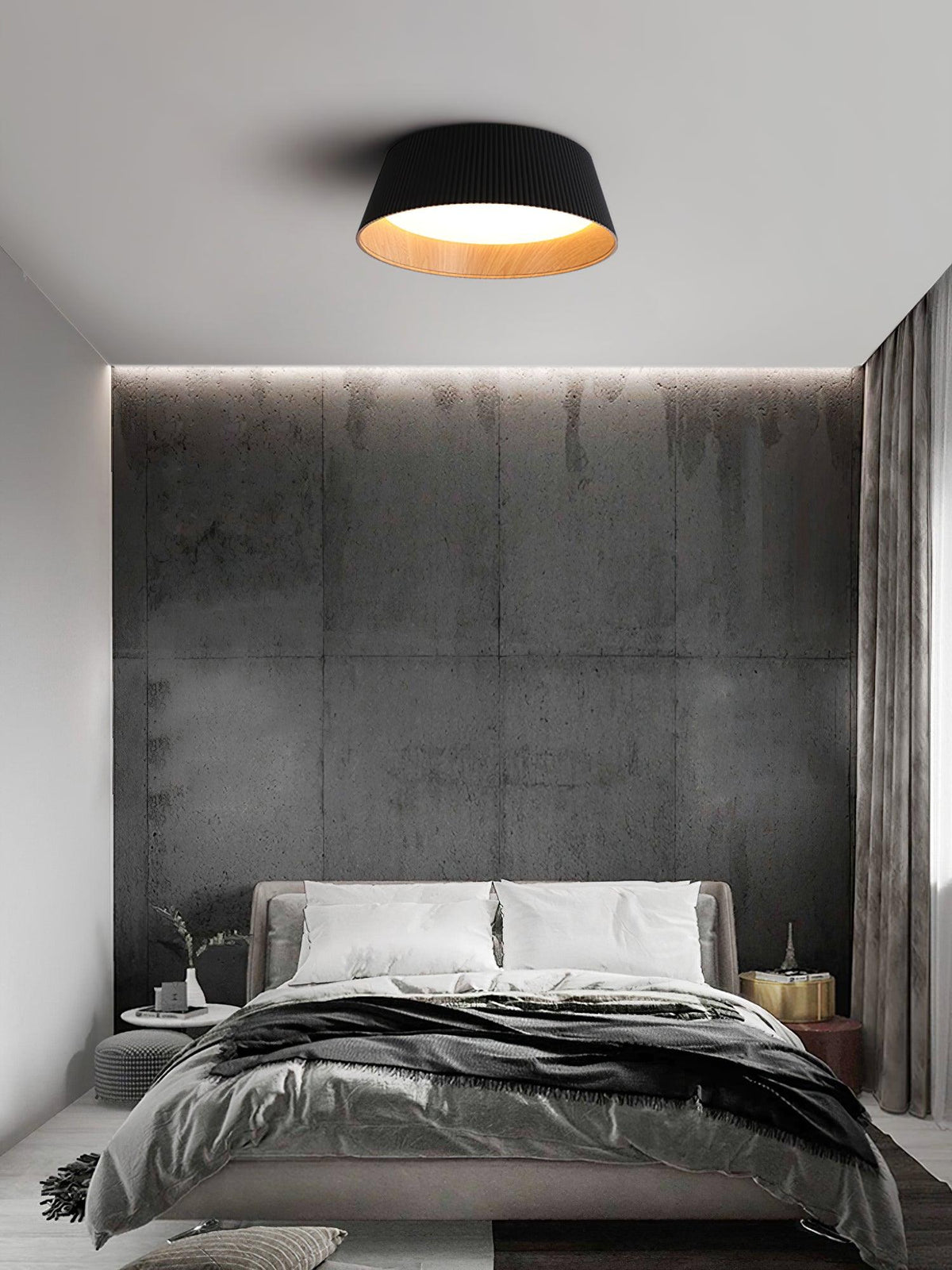 A black Clérachic ceiling light in a bedroom with a rough concrete-look wall and a grey bed with dark bedding.
