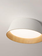 Close view of the large white fluted shade and wood-grain inner rim of this Clérachic ceiling light.