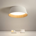 White fluted Clérachic ceiling light hanging high over a beige room with a low plinth and a small seat.