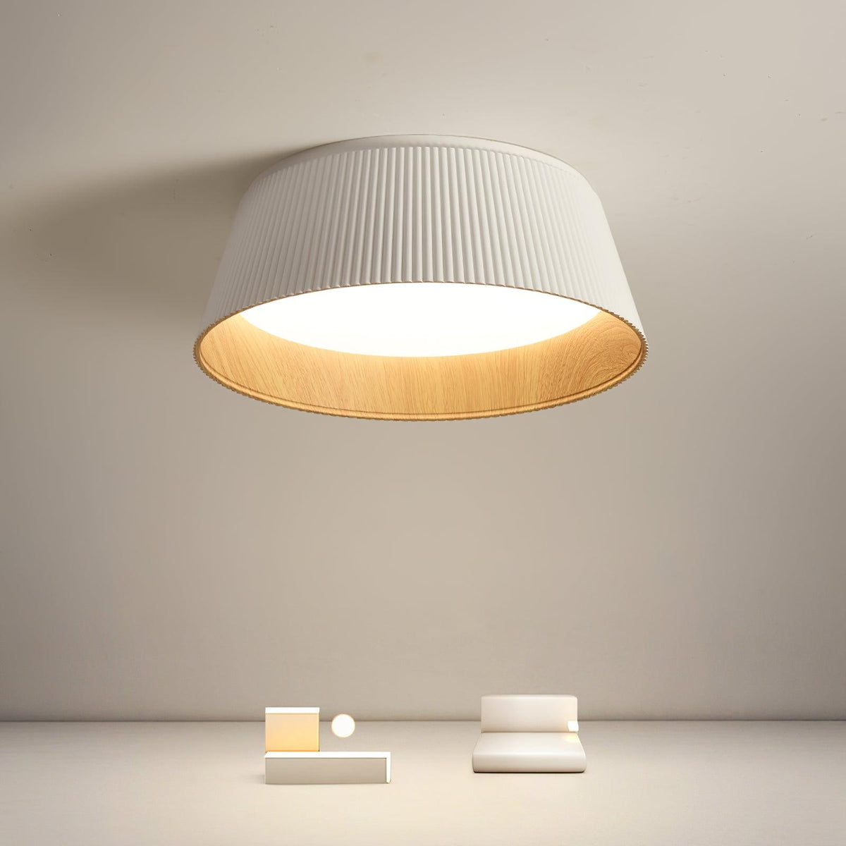 White fluted Clérachic ceiling light hanging high over a beige room with a low plinth and a small seat.