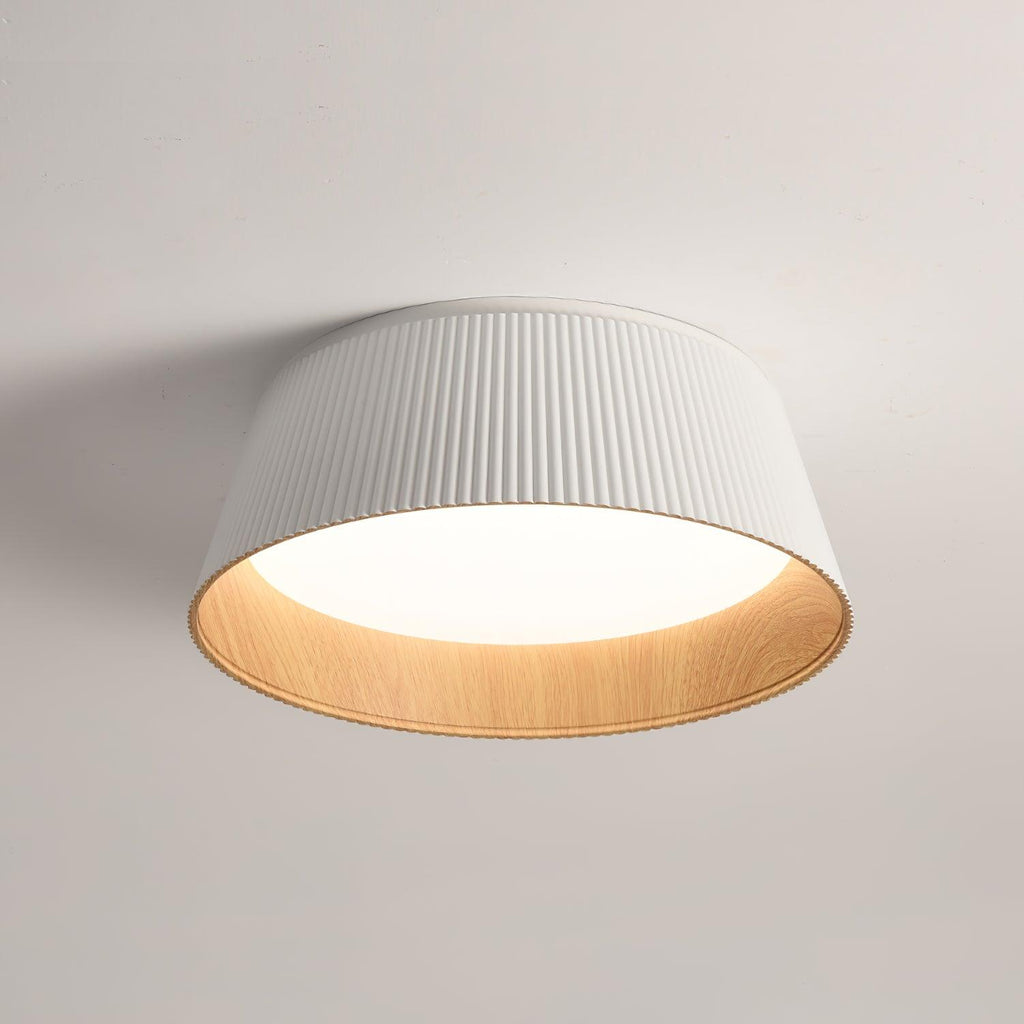 White fluted Clérachic ceiling light seen from below, its wood-grain inner rim and diffuser clear against the ceiling.