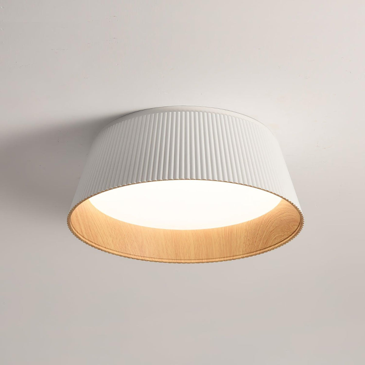 White fluted Clérachic ceiling light seen from below, its wood-grain inner rim and diffuser clear against the ceiling.
