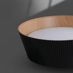 Close view of the black fluted outer wall, wood-grain inner rim and frosted diffuser of this Clérachic ceiling light.