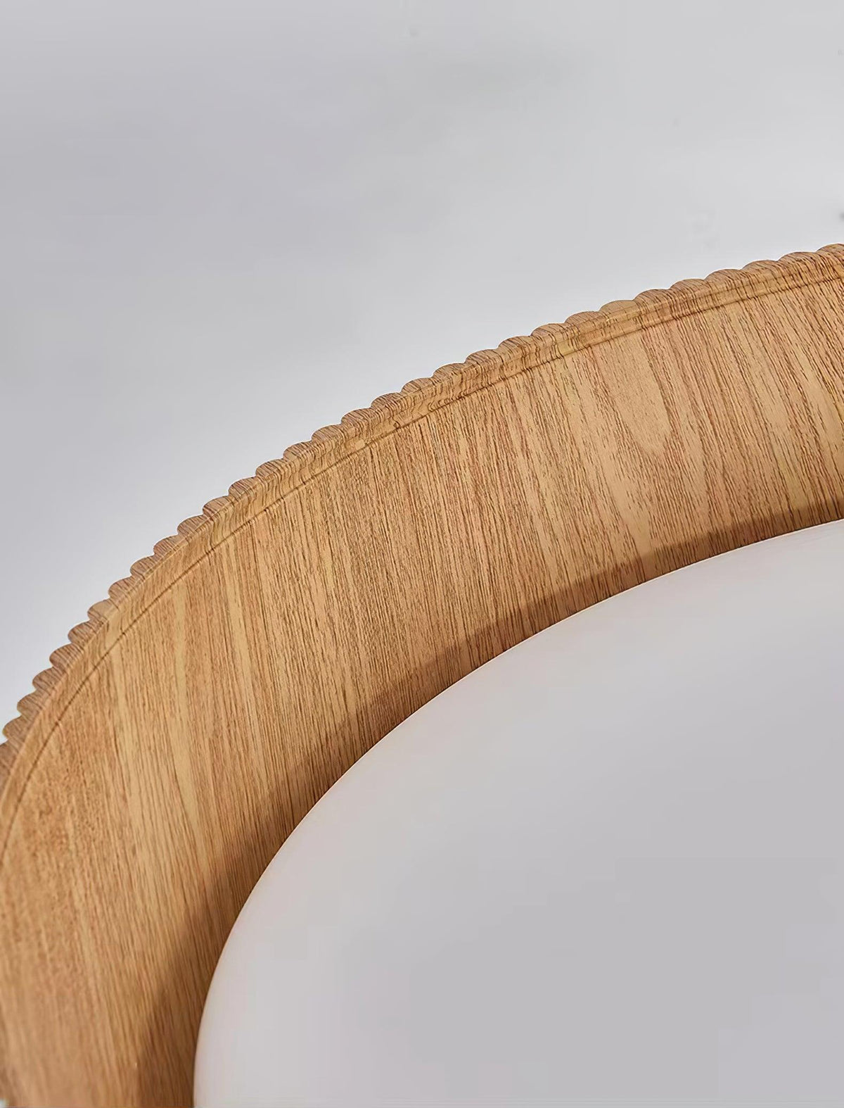 Close view of the serrated wood-grain rim and curved white diffuser of this Clérachic ceiling light.