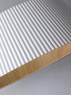 Close view of the white vertical ribbing and wood-grain interior edge on this Clérachic ceiling light.