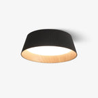 Black fluted Clérachic ceiling light with a lit diffuser and wood-grain interior, on a plain light backdrop.
