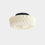 Head-on view of the beige Clérachic fluted opal glass flush ceiling light with its round black ceiling canopy.