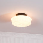 Close view beneath ornate crown molding of the white Clérachic fluted opal glass flush ceiling light, lit.