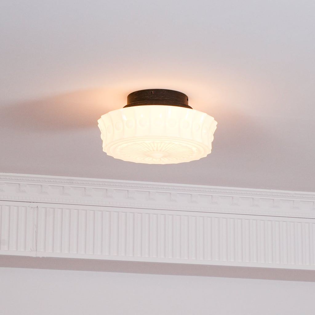 The white Clérachic fluted opal glass flush ceiling light seen from below in a softly lit hallway corner.