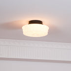 The white Clérachic fluted opal glass flush ceiling light seen from below in a softly lit hallway corner.