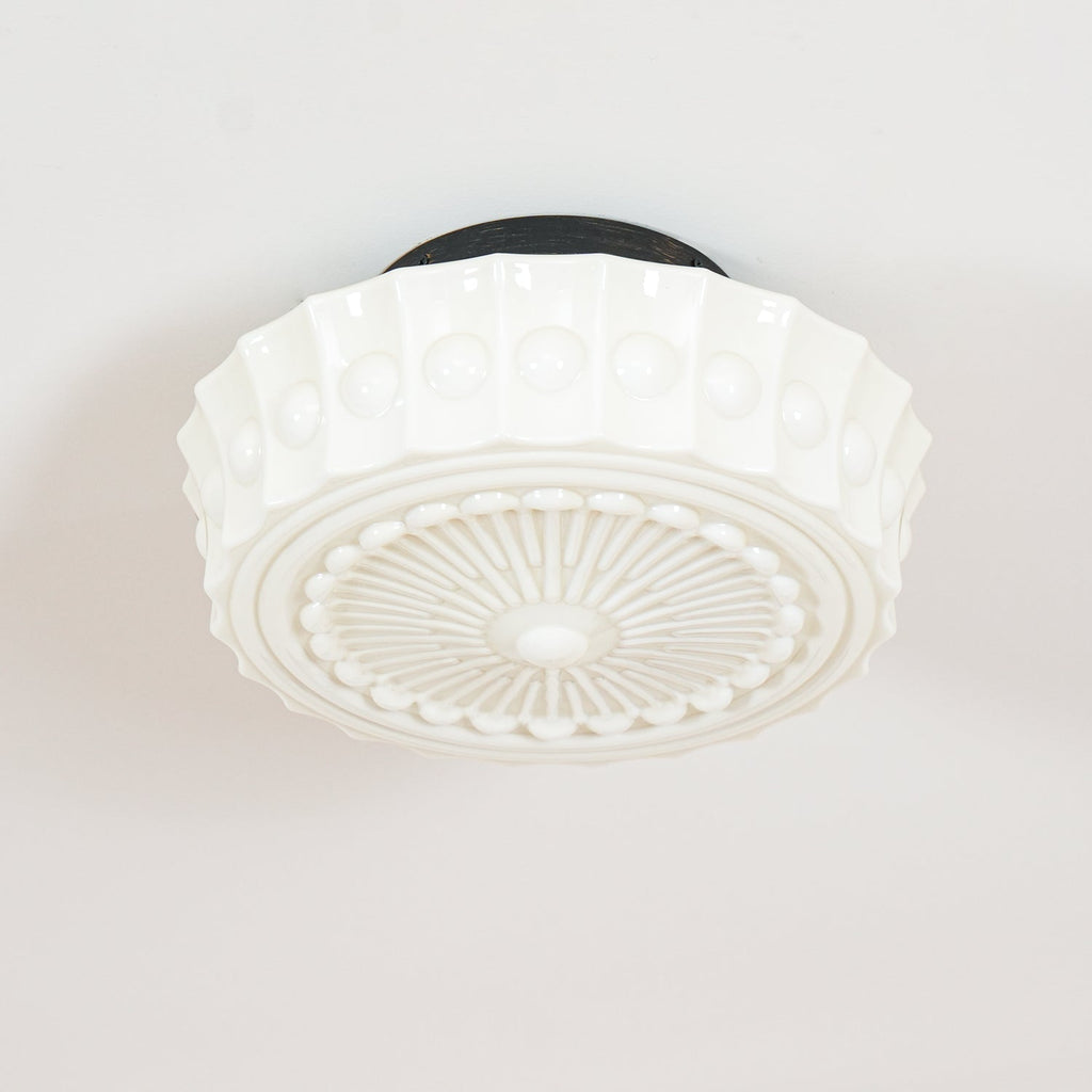 Close studio shot of the white Clérachic fluted opal glass flush ceiling light showing its raised boss detailing.