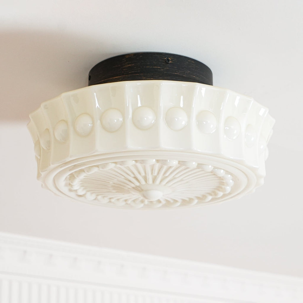 The white Clérachic fluted opal glass flush ceiling light with its round black ceiling canopy in close view.