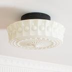 The white Clérachic fluted opal glass flush ceiling light with its round black ceiling canopy in close view.