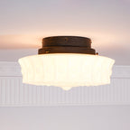 The beige Clérachic fluted opal glass flush ceiling light mounted with a black canopy against a plain ceiling.