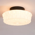 Close-up of the lit white Clérachic fluted opal glass flush ceiling light, casting a warm glow from its center.