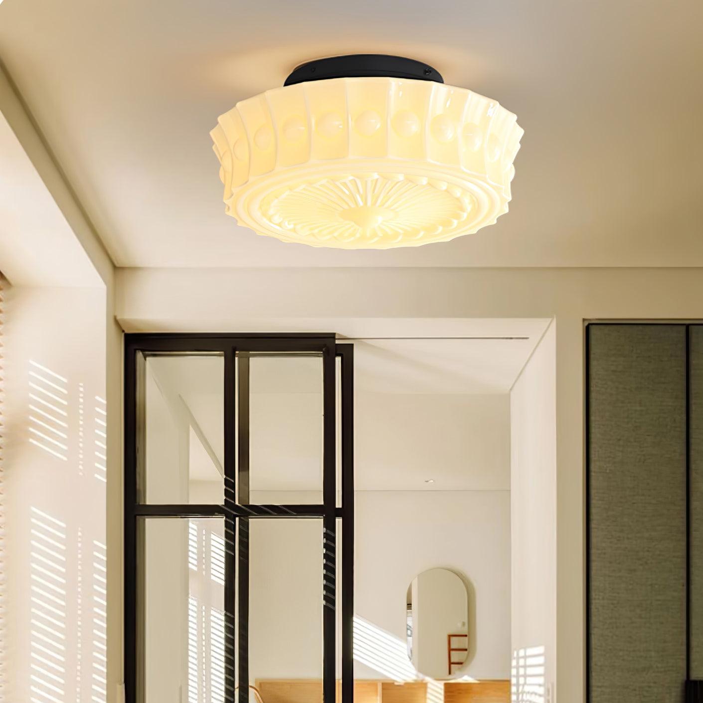 The white Clérachic fluted opal glass flush ceiling light lit above a room with a black-framed glass door.