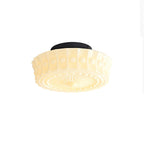 Close studio shot of the beige Clérachic fluted opal glass flush ceiling light glowing softly at its center.