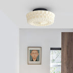 The white Clérachic fluted opal glass flush ceiling light lit in a bedroom with a framed portrait on the wall.