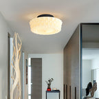 The white Clérachic fluted opal glass flush ceiling light lit in an entryway with a wood accent wall and driftwood.