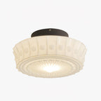 The white Clérachic fluted opal glass flush ceiling light lit on a plain backdrop, glass glowing from within.