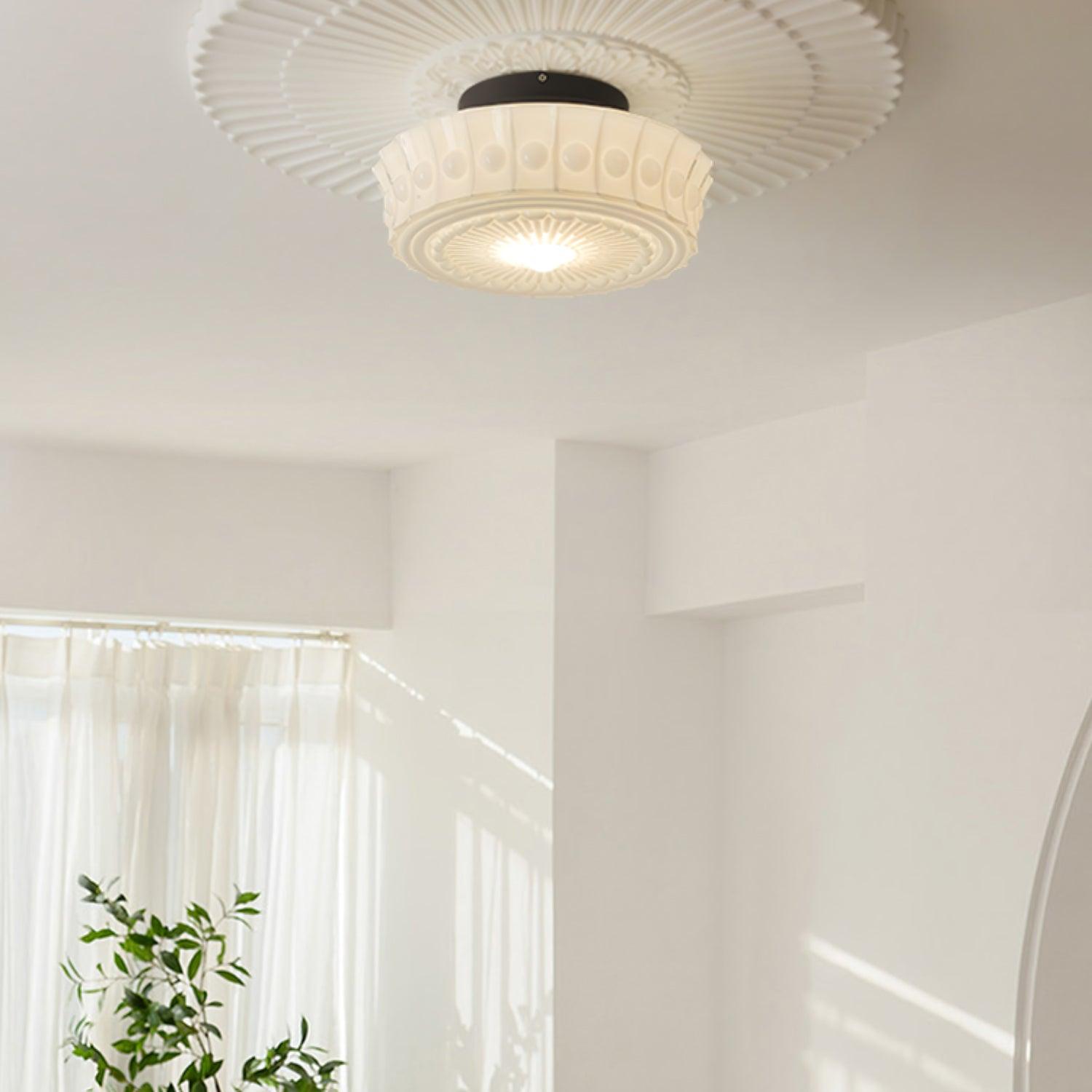 The white Clérachic fluted opal glass flush ceiling light lit beneath its fluted ceiling rosette, plants below.