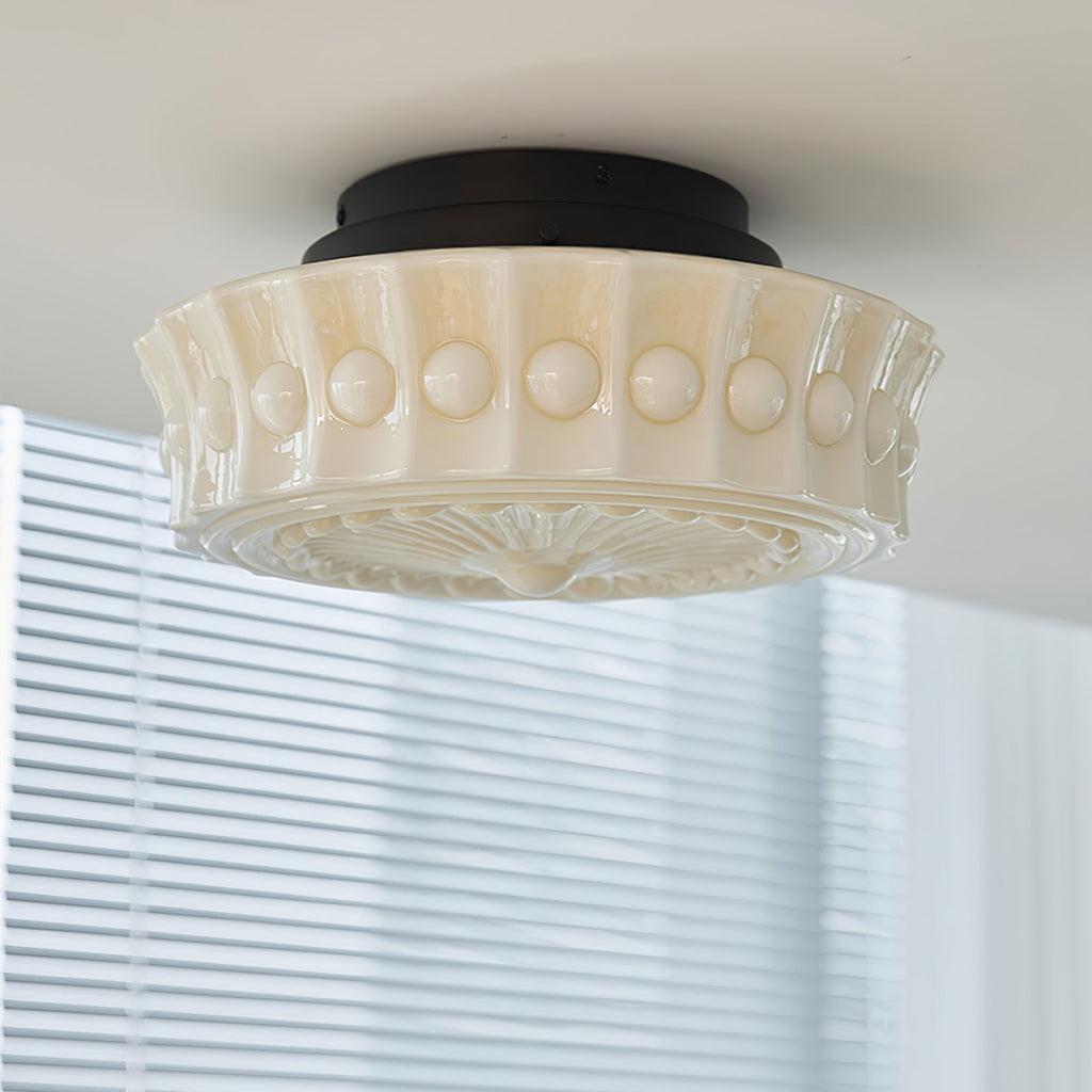 The beige Clérachic fluted opal glass flush ceiling light shown unlit close to window blinds in the background.