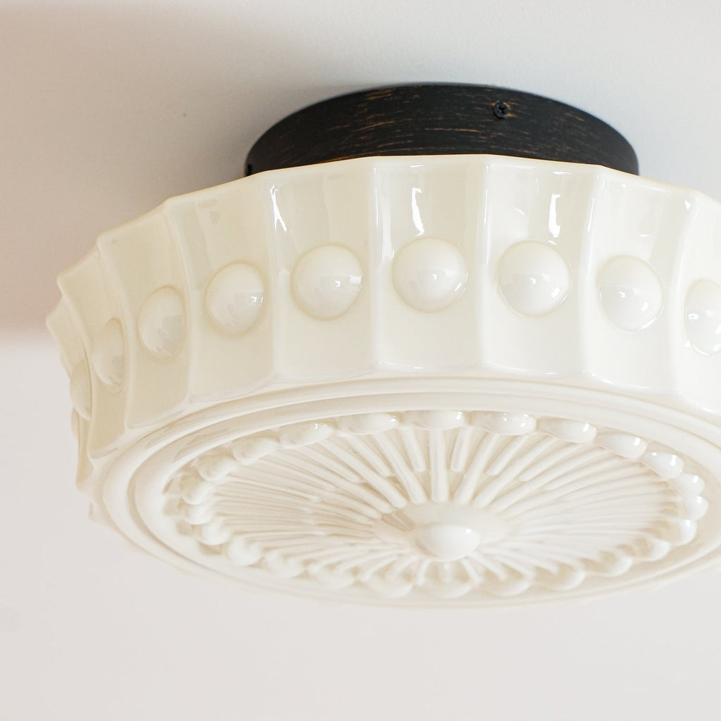 Detail shot of the white Clérachic fluted opal glass flush ceiling light's fluted band and black canopy.