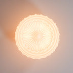 Extreme close-up of the lit white Clérachic fluted opal glass flush ceiling light's sunburst rosette underside.
