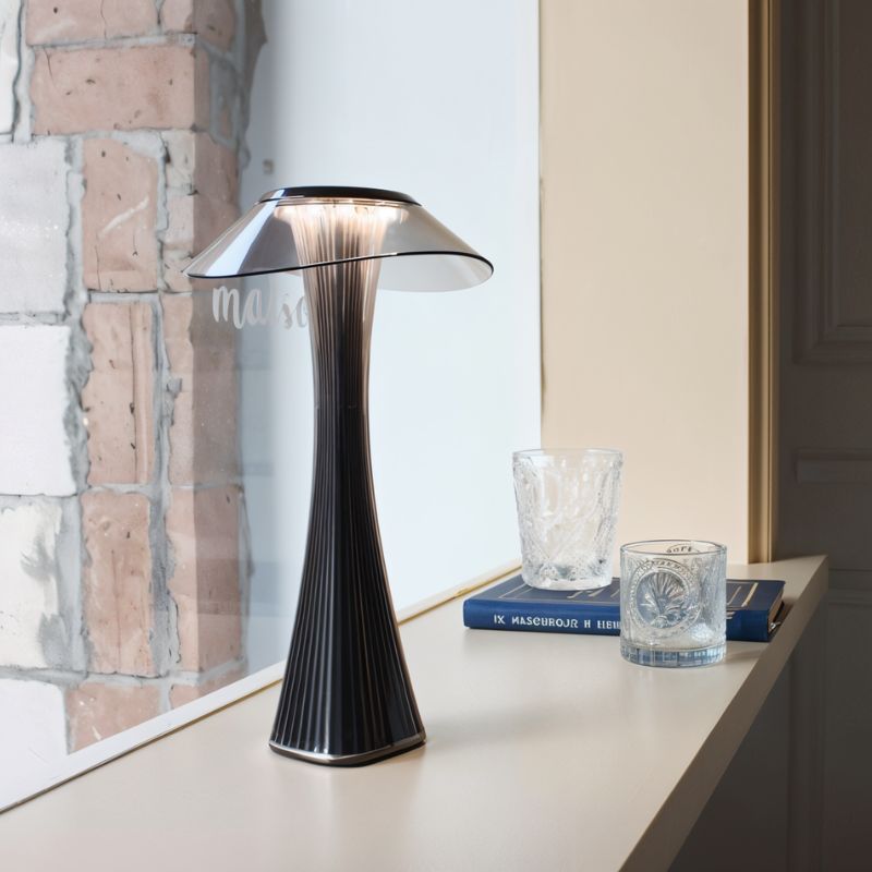 Clérachic black fluted table lamp on a windowsill beside a brick wall, with crystal glasses and a blue book