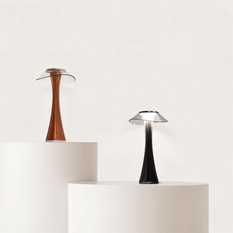 Pair of Clérachic fluted table lamps, one bronze and one black, on cream round plinths against a plain wall