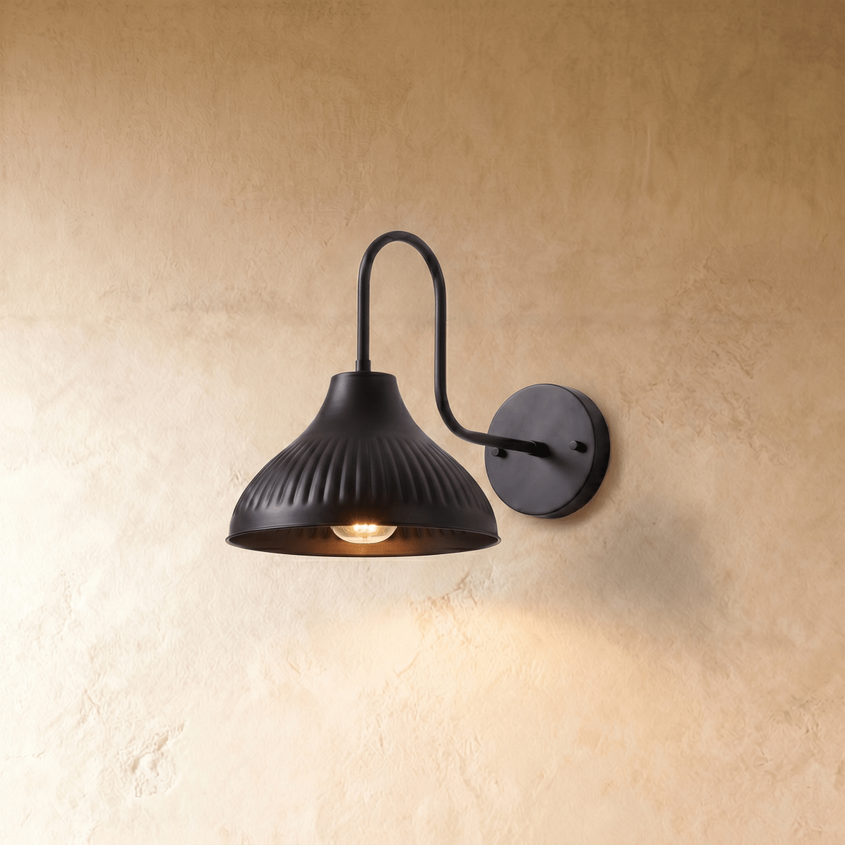 A Clérachic wall lamp in matte black, its fluted dome shade set on a long, curved swan-neck arm.