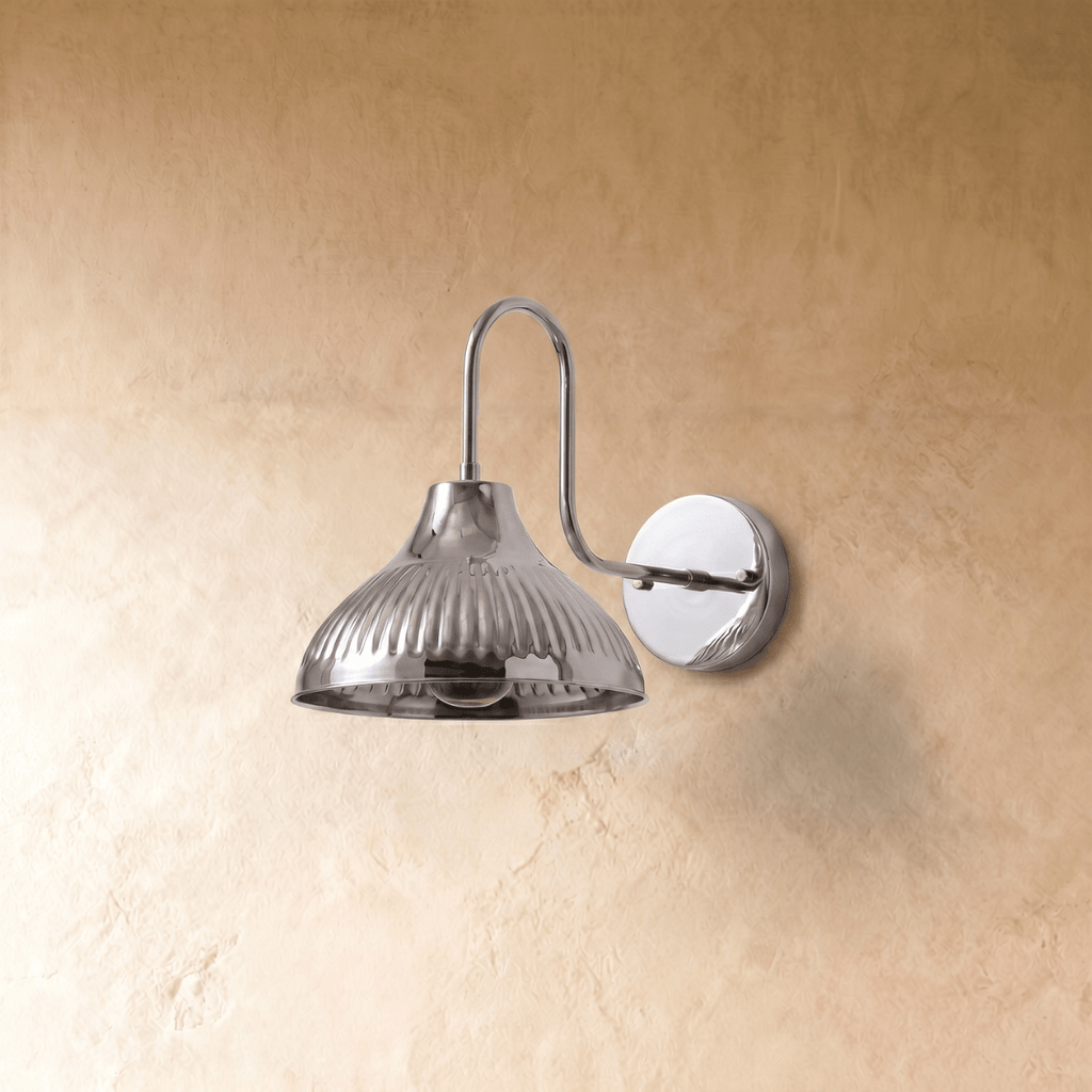 A chrome Clérachic wall lamp viewed from a different angle, the ribbed shade catching the light.