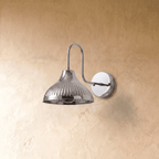 A chrome Clérachic wall lamp viewed from a different angle, the ribbed shade catching the light.