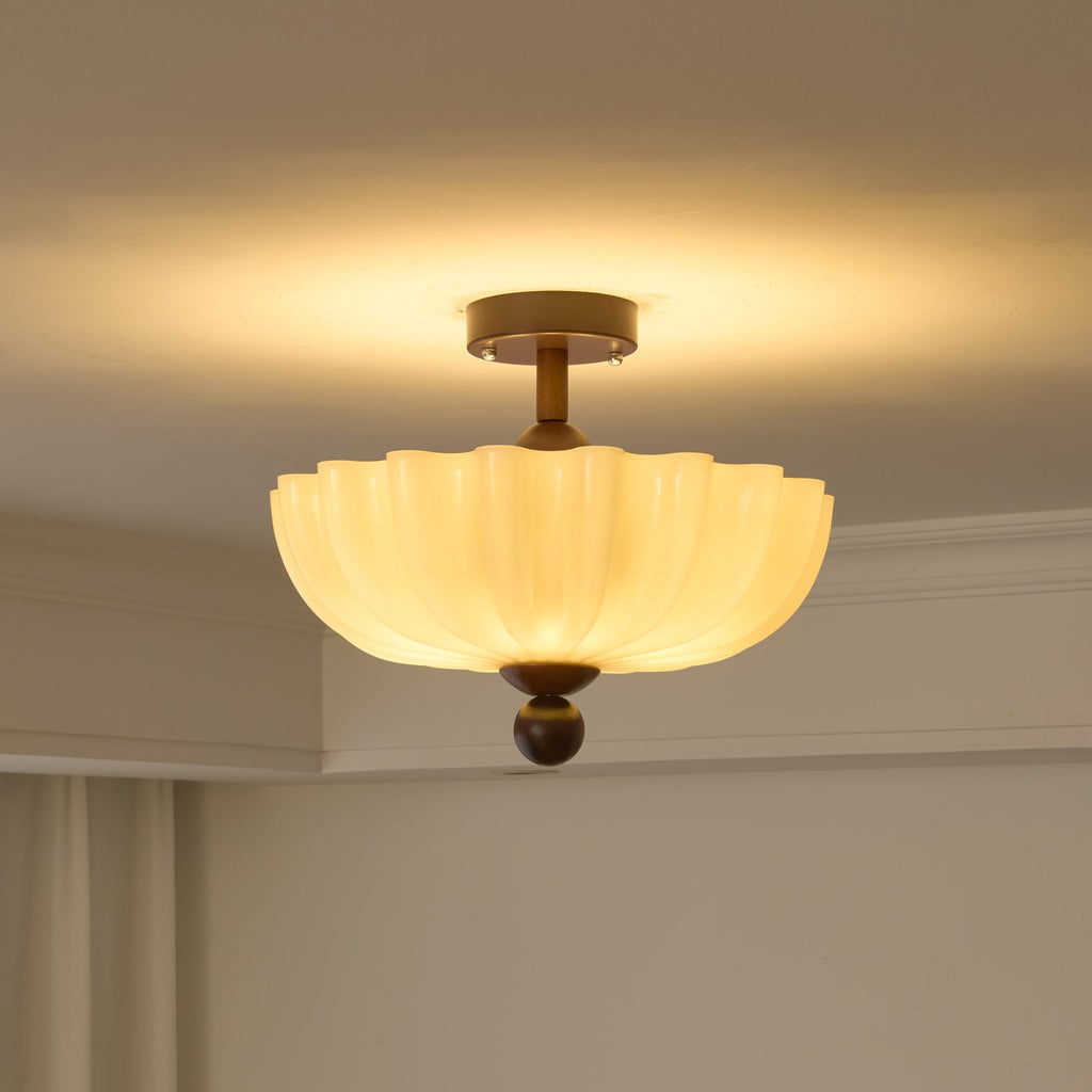 Scalloped Clérachic ceiling light switched on, a warm halo spreading across the cream ceiling above it.