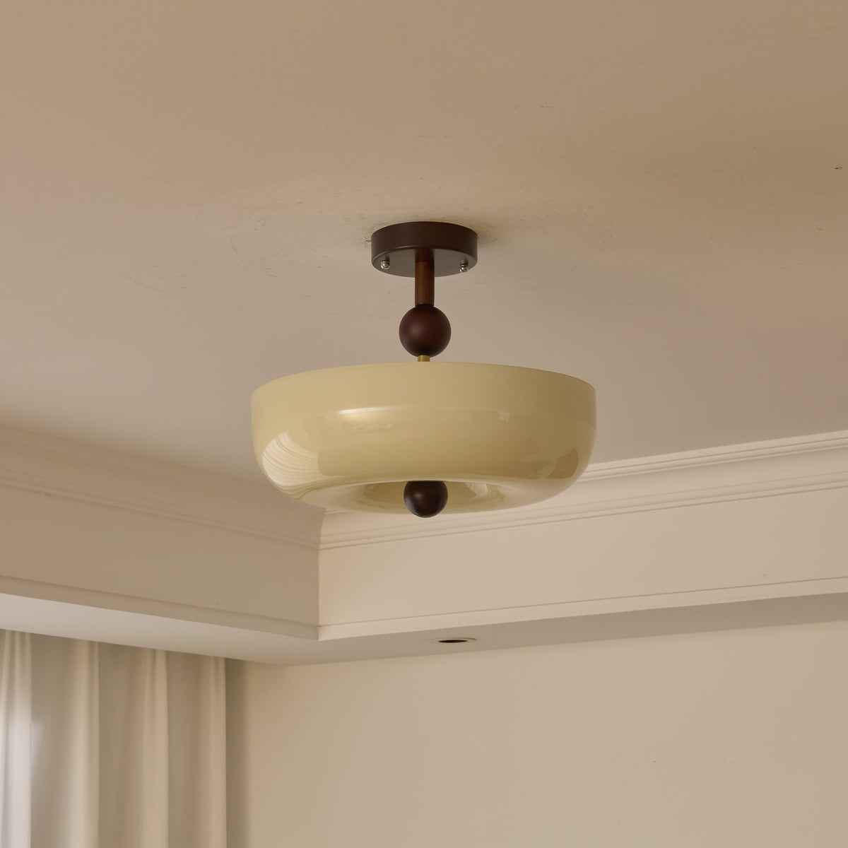 Unlit plain cream bowl shade with a walnut stem and ball, this Clérachic ceiling light hangs below a cream ceiling.