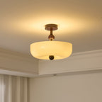 Lit round cream bowl shade on a short stem, a Clérachic ceiling light with a soft glow on the ceiling around it.