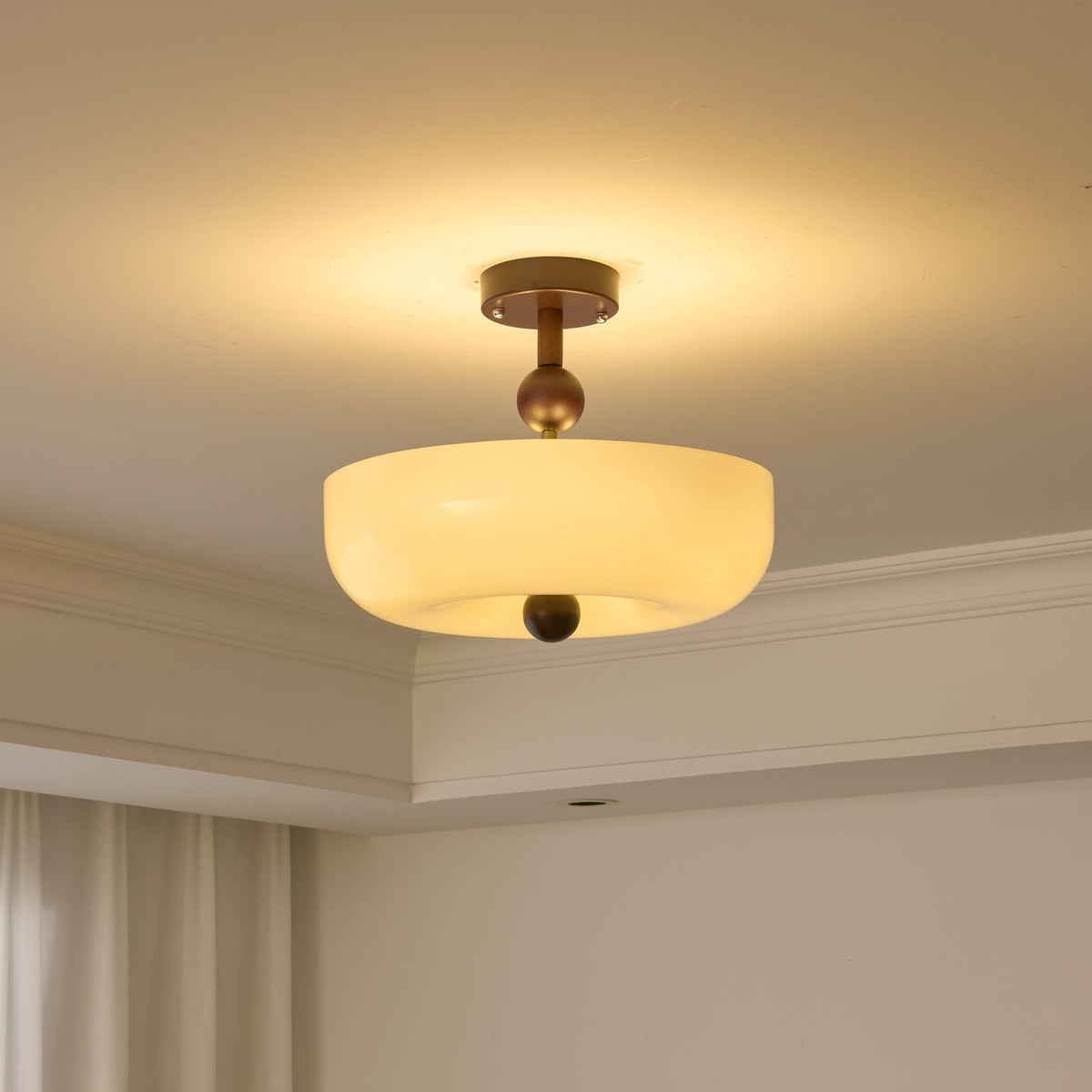 Lit round cream bowl shade on a short stem, a Clérachic ceiling light with a soft glow on the ceiling around it.