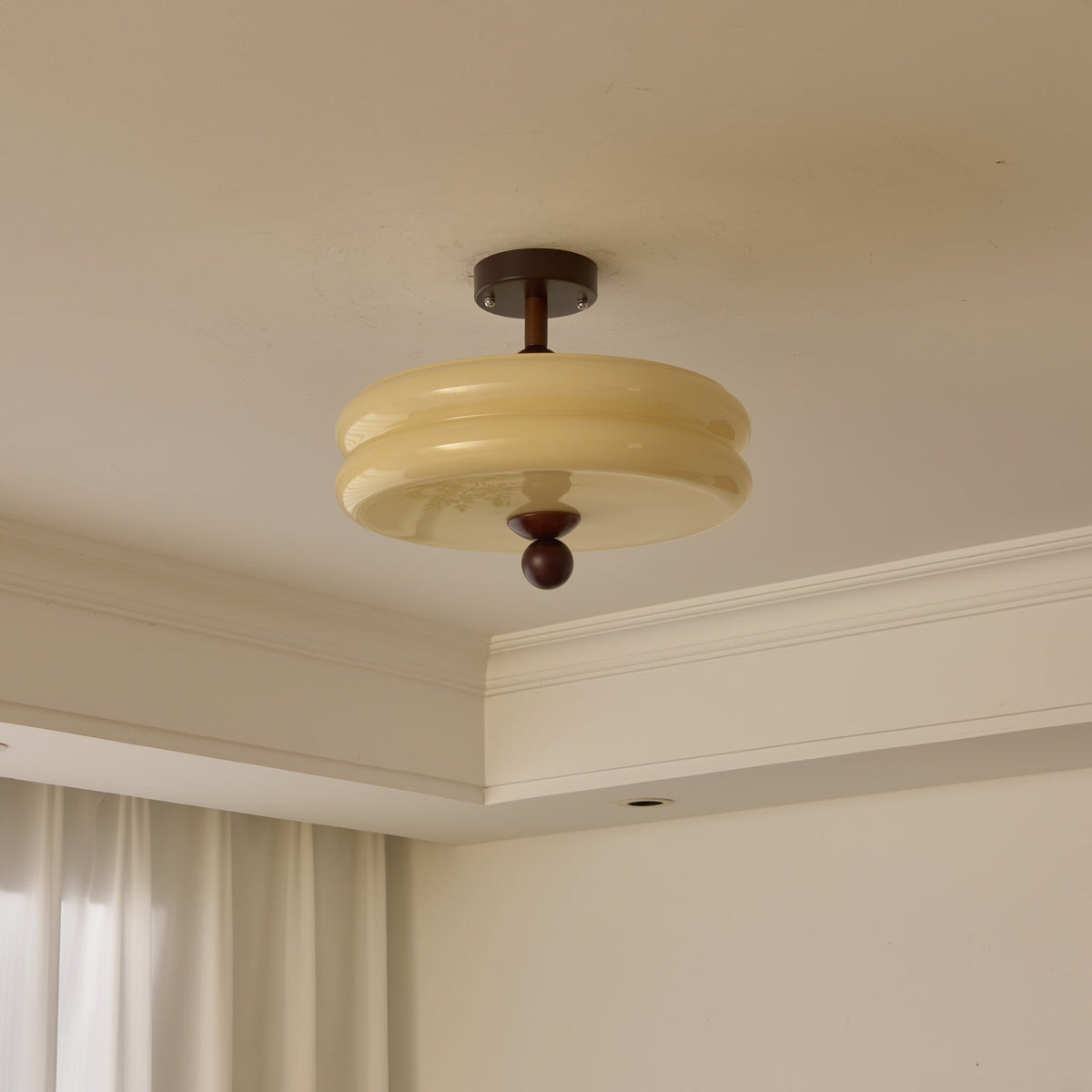 Unlit two-tier cream glass shade with a walnut stem and ball, this Clérachic ceiling light seen against a corner cornice.