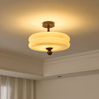 Lit double-tier cream shade from Clérachic, glowing yellow-white with a halo of light spreading over the ceiling.