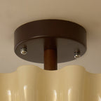 Close view of the round walnut-brown canopy, silver screws and wooden stem where this Clérachic light meets the ceiling.