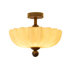 Lit scalloped cream shade with a walnut canopy and ball finial, this Clérachic ceiling light shown on a white background.
