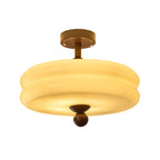Close view of the double-tier cream glass shade and walnut ball tip of this Clérachic ceiling light, lit, on white.