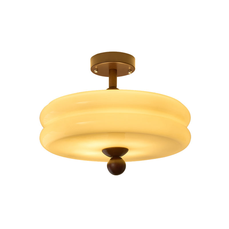 Lit two-tier cream glass shade with a walnut stem and ball finial, this Clérachic ceiling light on a white background.