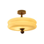 Lit two-tier cream glass shade with a walnut stem and ball finial, this Clérachic ceiling light on a white background.